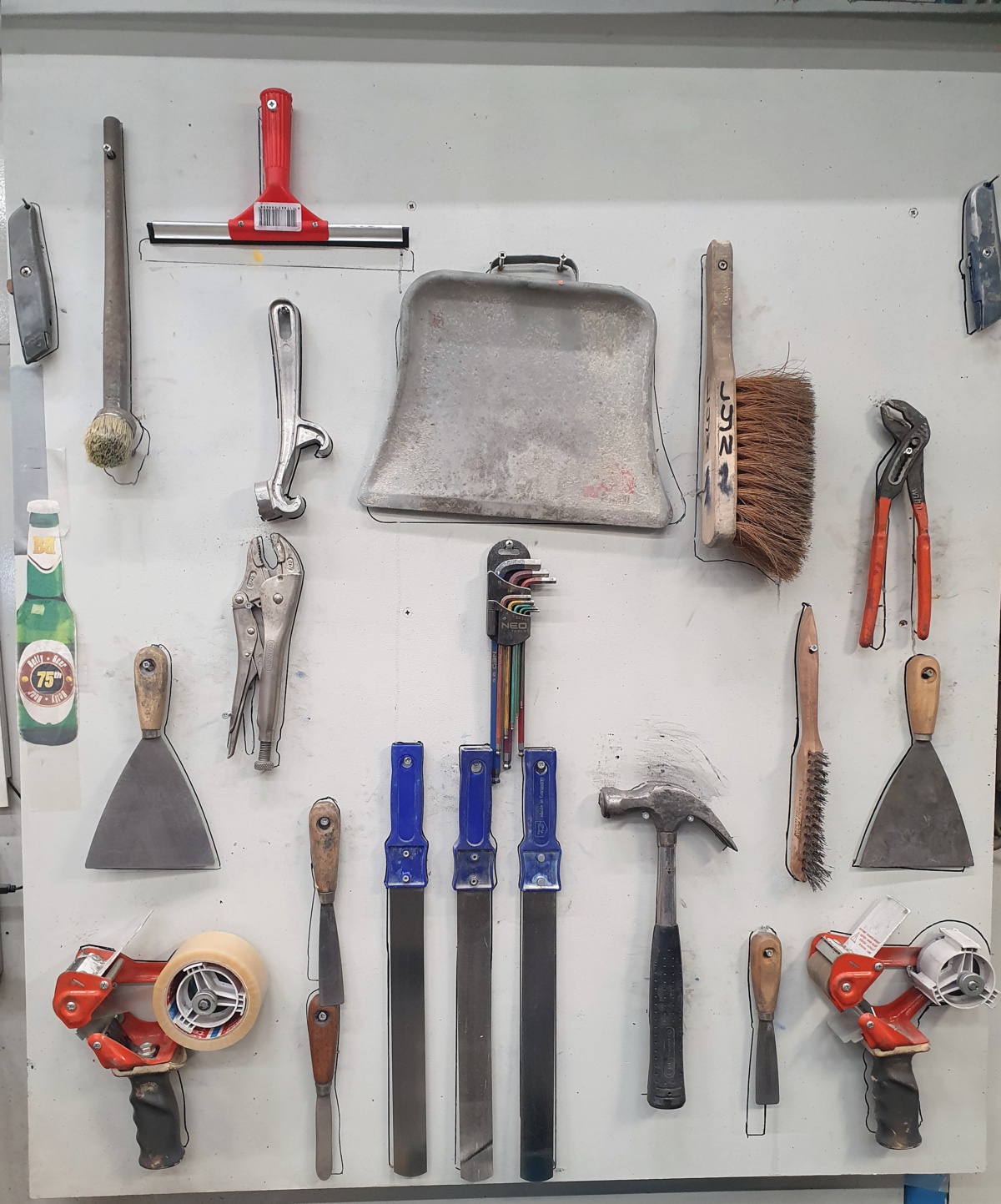 Een wand om gereerdschap op te bergen waarop duidelijk met contouren is aangegeven waar welke tool hoort te hangen.